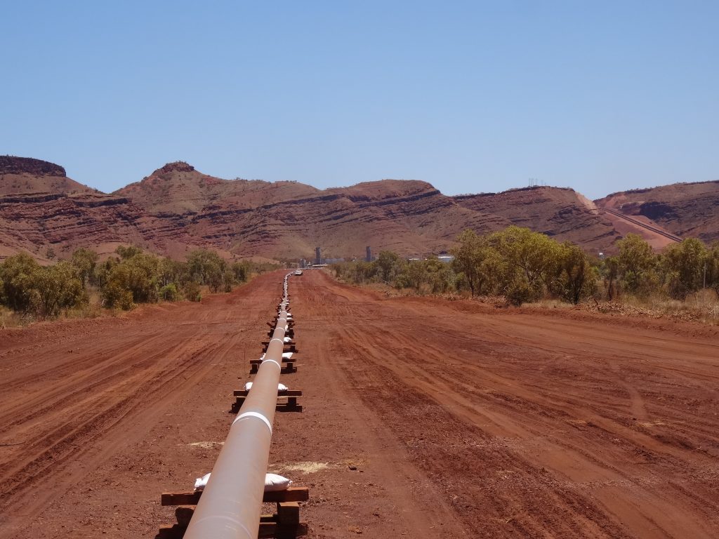 Fortescue Pipeline surrounded by red soil and clear blue sky mountain horizon