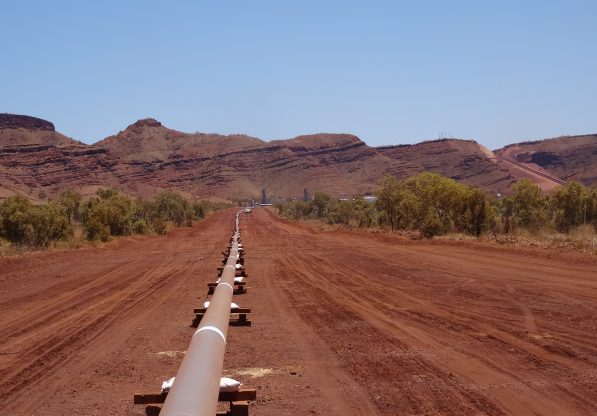 Fortescue Pipeline surrounded by red soil and clear blue sky mountain horizon